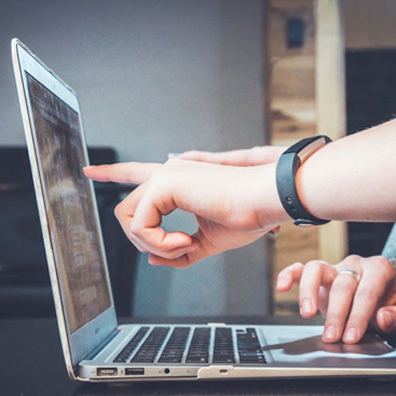 Two people pointing at computer screen